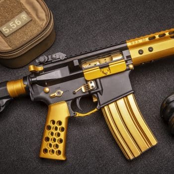 a gold and black rifle laying on a black surface
