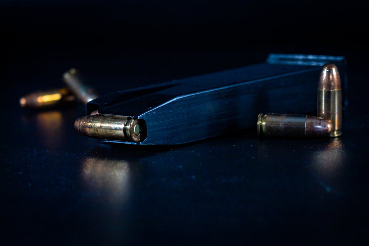 Detailed view of ammunition bullets and magazine on a dark surface.